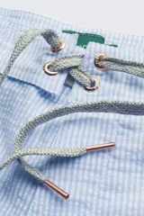 Short de baño celeste y blanco a rayas, con cintura fija, bolsillo lateral con cierre, cordón bicolor y suspensor de malla fina.