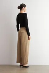 Pantalón pinzado de corte ancho, color beige, con bolsillos laterales y botamanga con vuelta.