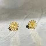 Par de aros tipo botón con forma de flor, hechos en plata 925 con acabado en oro de 18k y circonias amarillas.