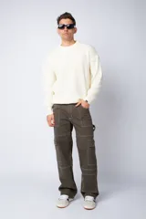 Pantalón tipo carpintero de corte relaxed fit y tiro medio, confeccionado en denim negro con costuras a contracolor en blanco. Presenta múltiples bolsillos cargo laterales, un bolsillo con cierre en la parte inferior y presillas utilitarias.