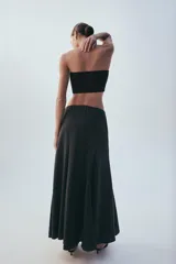 Falda midi negra de tiro medio, confeccionada en tejido fluido con acabado satinado y diseño evasé.