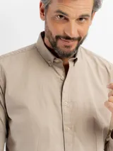 Camisa de manga larga color azul marino, confeccionada en algodón, con cuello abotonado y cierre frontal de botones.