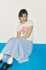 Falda midi celeste con rayas verticales finas en azul marino, de tiro alto, con pliegues en el delantero y cierre lateral con cremallera oculta.