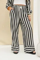 Pantalón de rayas verticales en blanco y negro, de corte ancho, con cintura elástica ajustable mediante cordón blanco.