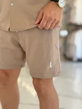 Bermuda blanca de tejido texturizado, con pequeño bordado oscuro en la parte inferior izquierda.