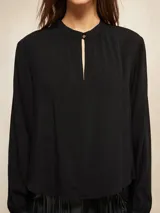 Blusa de manga larga color blanco, con cuello mao y pequeña abertura frontal con cierre de botón. Presenta un diseño de corte recto y tejido ligero.