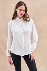 Blusa negra con cuello mao, calce al cuerpo y mangas 3/4 con puños abotonados. Cierre frontal con botones.