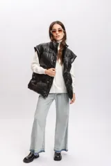 Chaleco puffer marrón de cuero sintético con cuello alto y cierre frontal con botones a presión.