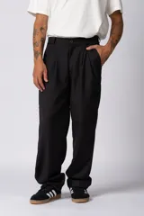 Pantalón sastrero de corte baggy con pinzas frontales, cierre de botón y bolsillos laterales. Presenta una silueta amplia y relajada con caída recta.