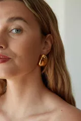 Aros de acero quirúrgico hipoalergénico con acabado dorado y diseño abombado de forma orgánica tipo huevo.