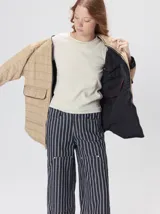 Campera reversible capitoneada con cierre frontal. Un lado es de color negro y el otro es de color beige, ambos con diseño acolchado. Cuenta con cuello redondo, mangas largas y bolsillos laterales.