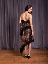 Pollera corta de lentejuelas con diseño asimétrico y terminaciones en puntilla negra. Presenta una cintura elástica para mayor comodidad.