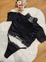 Conjunto de lencería compuesto por un top de manga corta y una tanga, confeccionados en terciopelo negro con detalles de encaje en cuello, mangas y bordes. El top presenta un diseño tipo crop y la tanga es regulable.