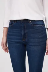 Pantalon jean de tiro alto con corte flare y terminación desflecada en el ruedo. Presenta un diseño clásico de cinco bolsillos con costuras en contraste.