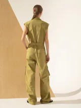 Mono color verde oliva, con cuello camisero, sin mangas, bolsillos frontales y laterales tipo cargo, y cinturón de lazo.