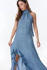 Vestido midi de lino color azul, con escote halter y ruedo asimétrico con volado.