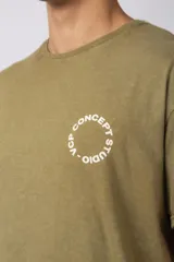 Remera verde militar de algodón con efecto lavado gastado y corte oversize. Estampa circular blanca con texto "VCP CONCEPT STUDIO" en el frente.