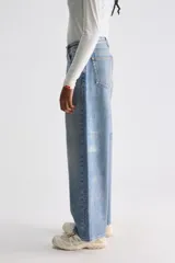 Jean de tiro bajo confeccionado en denim rígido de algodón, de color azul con efecto deslavado. Presenta perneras anchas de corte holgado, cierre frontal con botones y diseño de inspiración urbana.