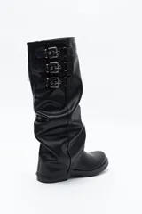Bota de caña alta color negro, con diseño utilitario, puntera redondeada y taco bajo. Presenta un efecto fruncido en la caña y tres hebillas metálicas decorativas.