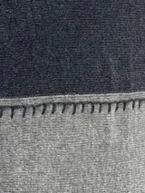 Pashmina de lana con diseño de bloques de color en gris oscuro, gris claro, blanco y negro. Presenta costuras decorativas en contraste.