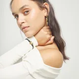 Pulsera ajustable con hilo elástico negro y dije central con forma de corazón tridimensional bañado en oro 18k. Incluye un cierre o tope cilíndrico bañado en oro 18k.