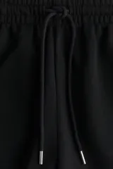 Short negro de felpa liviana, confeccionado en mezcla de algodón. Presenta cintura elástica con cordón ajustable y bolsillos laterales discretos.