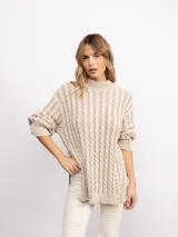 Sweater de punto con diseño de trenzas verticales, cuello alto y silueta oversize. Presenta un patrón bicolor en tonos azul y azul oscuro, con mangas largas y terminaciones en tejido acanalado.