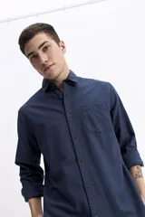 Camisa de manga larga color azul marino con textura, cuenta con cuello clásico, cierre frontal con botones y un bolsillo en el pecho.