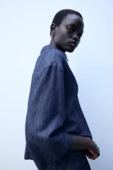 Camisa de lino azul, con cuello solapa, escote en V y mangas por debajo del codo.