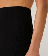 Falda midi negra de rib, con abertura lateral.
