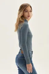 Polera de manga larga con cuello alto, confeccionada en tejido de punto acanalado con diseño de rayas horizontales en color marrón y turquesa. Presenta un bordado pequeño en el pecho y un calce ajustado al cuerpo.