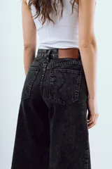 Jean wide leg de tiro alto en color negro con efecto acid wash y diseño de pernera ancha.