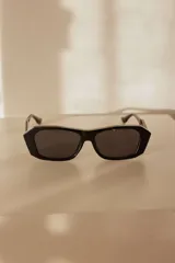 Lentes de sol con diseño estructurado, líneas limpias y frente recto en color negro.