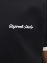 Remera negra de manga corta con calce relajado y cuello redondo. Cuenta con ribetes en contraste color beige en el cuello y los puños, además de un pequeño bordado en el pecho con texto en tipografía cursiva.