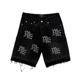 Short de jean negro con diseño de strass aplicado en toda la superficie, formando logotipos repetidos y detalles de tachas. Presenta bordes deshilachados en el ruedo y cierre frontal con botón metálico.