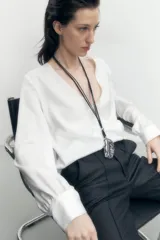 Pantalón negro de corte recto, con cintura alta, bolsillos laterales y cierre frontal con botón y cremallera.