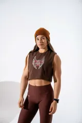 Musculosa crop top de algodón elastizado color marrón, con diseño gráfico frontal de alas y texto en tonos blanco y rosado.