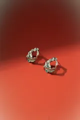 Aros de diseño orgánico con textura irregular y acabado metálico plateado, con cierre de perno.