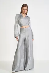 Camisa gris de satén con corte cropped, cuello clásico, mangas largas abullonadas y cierre cruzado con lazo.