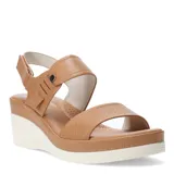 Sandalias de plataforma con diseño de tiras en cuero sintético color tostado. La tira delantera presenta una textura grabada, mientras que la tira trasera incluye un cierre con hebilla y detalle metálico. Posee una base de plataforma blanca con diseño estriado.