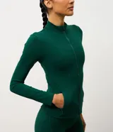 Campera deportiva Get Over de microfibra, con cuello alto, mangas largas, cierre frontal con cremallera y bolsillos laterales funcionales. Presenta un diseño ajustado con costuras verticales que realzan la silueta.