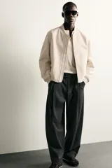 Pantalón de corte balloon fit en color gris oscuro, confeccionado en tejido con viscosa. Presenta pliegues frontales, cintura ajustable con cinturón integrado, bolsillos laterales y bolsillos traseros de doble vivo. Cierre frontal con cremallera y botón.
