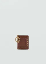 Billetera pequeña de cuero sintético color marrón, con diseño de tachuelas metálicas doradas en el frente y llavero incorporado. Cuenta con cierre de solapa con botón a presión y múltiples ranuras para tarjetas.
