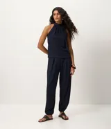 Pantalón aladín de tejido texturizado color azul marino, con volumen amplio en las piernas, cintura elástica y pliegues delanteros.