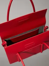 Cartera de hombro Calvin Klein estructurada, color rojo vibrante, con solapa frontal y bolsillo exterior con el logo grabado en metal plateado. Posee asas tubulares superiores y una correa ajustable para llevar cruzada.