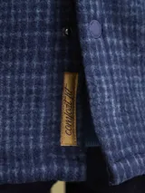Sobrecamisa de tejido polar con estampado abstracto en tonos rojizos y azul marino. Presenta cuello clásico, cierre frontal con botones a presión, dos bolsillos frontales con solapa en el pecho y un parche decorativo.