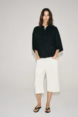 Camisa amplia confeccionada en hilatura con lyocell y ramio, color celeste, con cuello solapa, manga por debajo del codo, detalle de pliegue en la espalda y cierre frontal con botones ocultos por solapa.