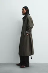 Trench de corte relajado confeccionado en tejido compacto de algodón. Presenta cuello solapa en color contraste, cierre frontal con botonadura oculta, bolsillos de vivo en la cadera y cintura ajustable con cinturón del mismo tejido. Las mangas largas cuentan con puños con trabilla y el bajo es ajustable en el centro de la espalda.