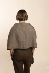 Chal de lana fina sin teñir con diseño de cuadros sutiles, cierre frontal con alamar y bolsillos de cuero metalizado. Presenta terminaciones con flecos en el ruedo y un calce estructurado en los hombros.