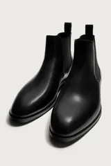 Bota Chelsea de hombre en color marrón oscuro, con diseño liso, punta afilada, elásticos laterales y tirador trasero.